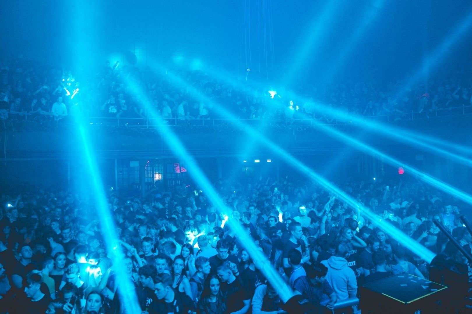 Crowded dance club washed in blue light and sweeping beams