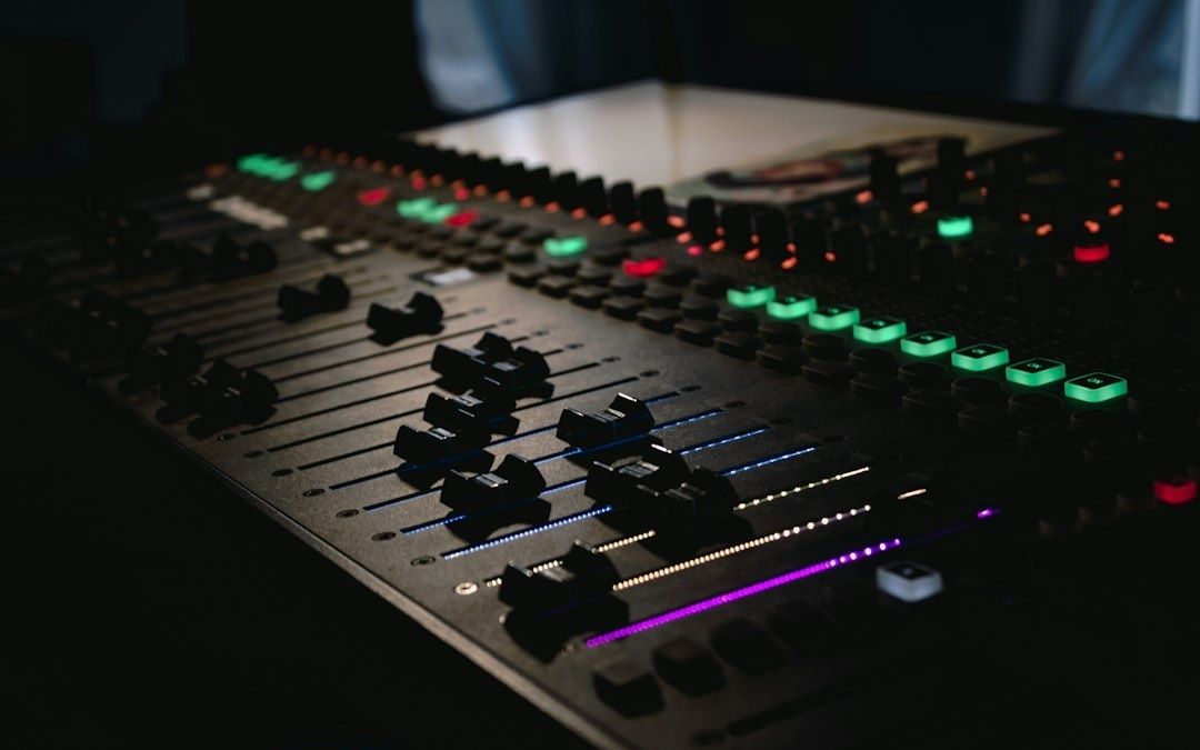 Close-up of an illuminated audio mixing console in a dark venue