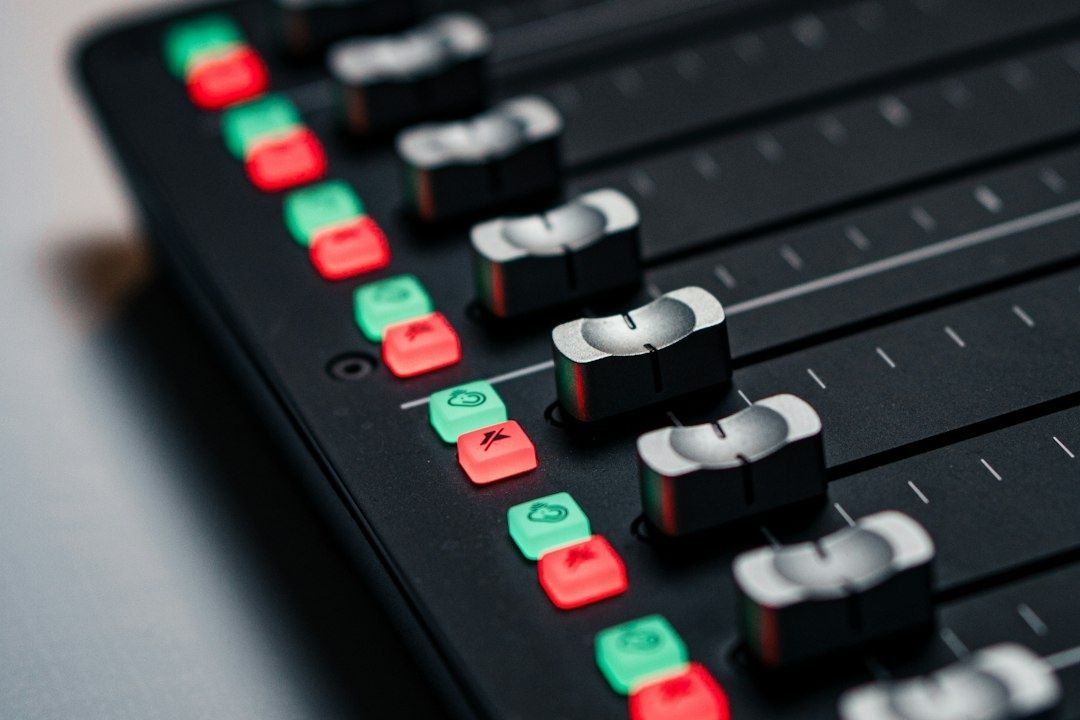 Close-up of a professional audio mixer with faders and illuminated controls